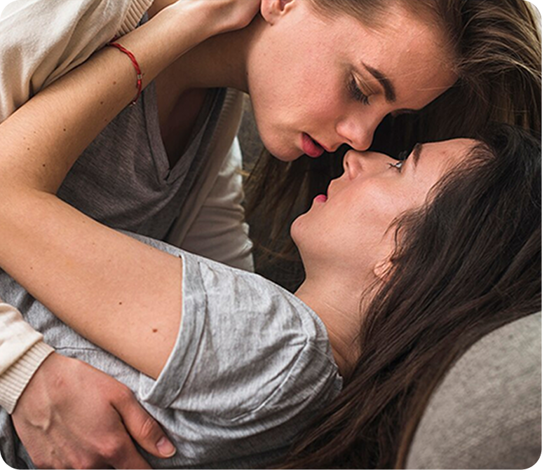 DoubleList graphic of 2 women in an intimate embrace on a couch for a bisexual hookup.