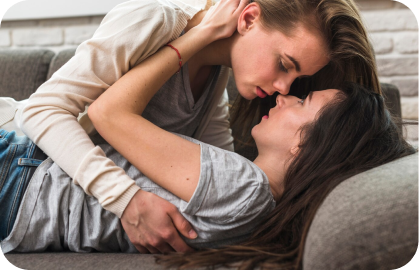 Stock photo of 2 women in an intimate embrace on a couch for a bisexual hookup.